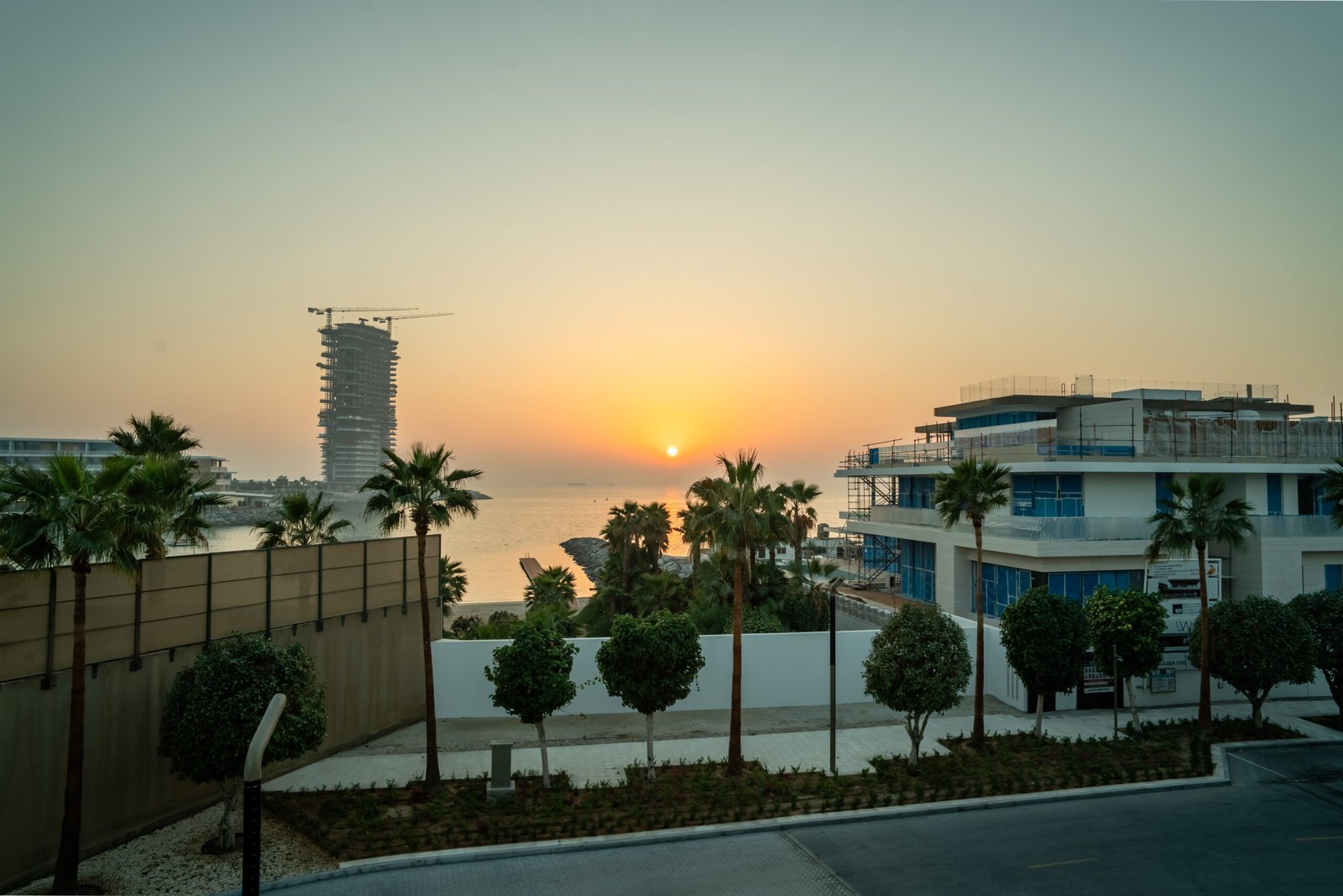 Luxury apartments with sea view at sunset, featuring modern architecture, palm trees, and beachfront location in Dubai