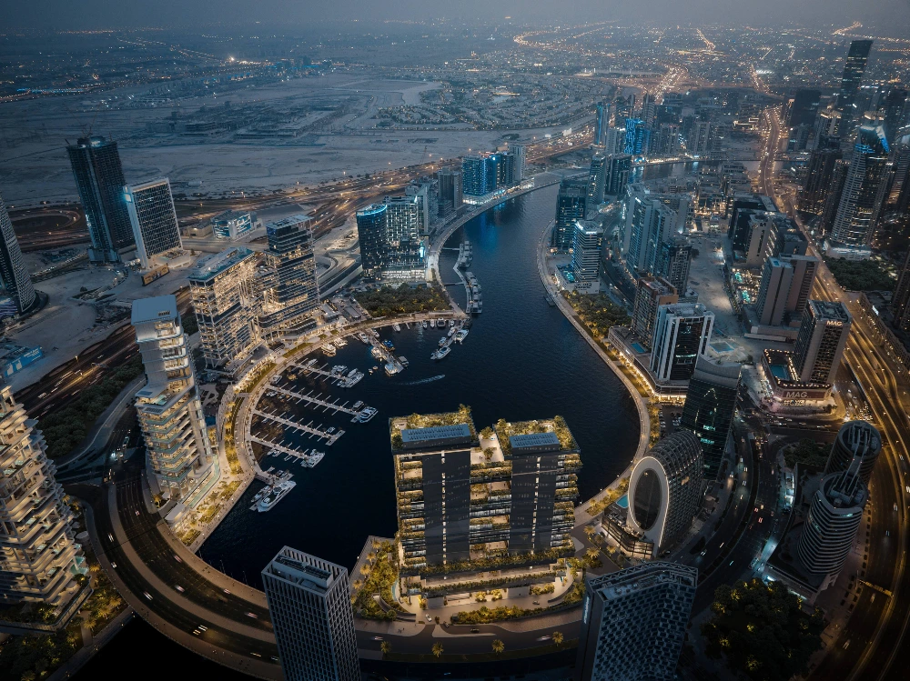 Aerial night view of a yacht-filled Dubai marina surrounded by illuminated waterfront apartments